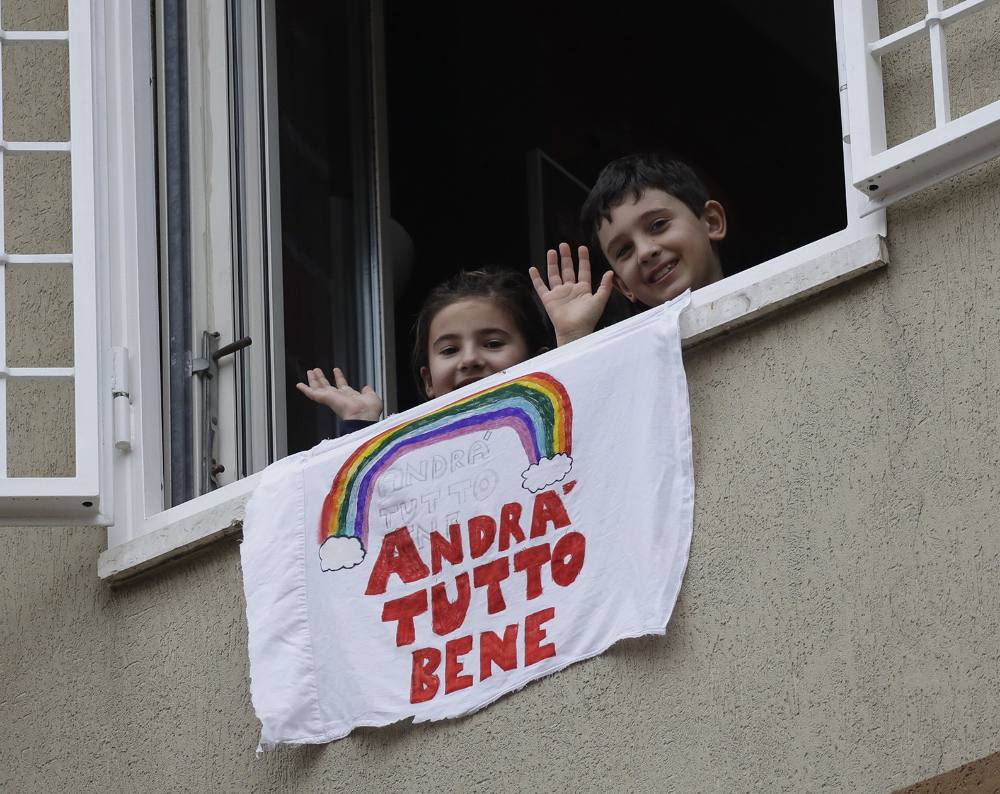Francesco and Greta Innominati wave after placing a banner reading "Everything is gone be all right". Lessons from covid-19 - Rome, March 13, 2020. Image: Alessandra Tarantino/AP.